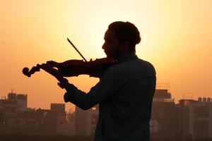 músico tocando violín. concepto de música y tono musical. imágenes de silueta de hombre músico foto