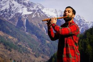 joven tocando la flauta india bansuri en las montañas foto