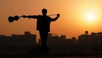 músico tocando violín. concepto de música y tono musical. imágenes de silueta de hombre músico foto