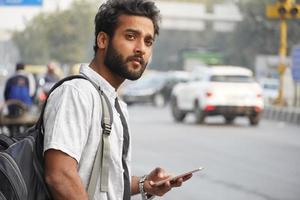 A man waiting for auto or bus and using mobile phone