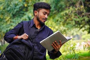 imágenes de estudiantes indios estudiante indio mirando en un libro con una bolsa foto