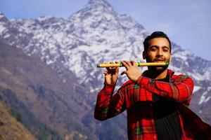 bansuri indian instrument Young boy playing bansuri Indian flute in mountains photo