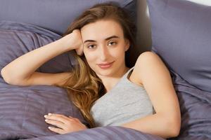 Woman lying on her bed looking at the camera with a smile photo