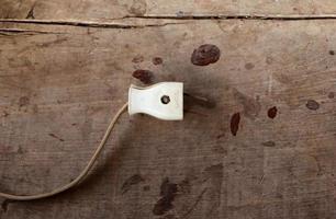 Old worn out electric plug device on wooden table photo