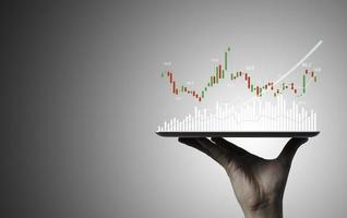 Trader holding Tablet and touching to technical graph chart  for analysis stock market data and speculator investment concept. photo