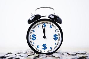 pantalla de impresión de signo de dólar dentro del despertador en un montón de monedas para el concepto de gestión de tiempo y dinero. foto