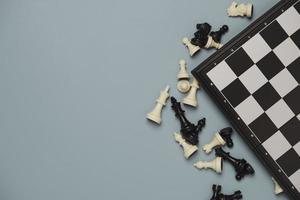 Top view of chess pieces with chess board on blue background for leisure and business strategy concept. photo