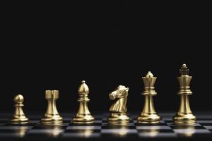 Golden chess include king queen horse ship and pawn on dark background.
