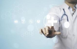 Doctor hand touching white hospital sign and healthcare icons with copy space for assurance and insurance concept. photo