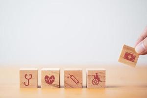 poner y apilar cubos de bloques de madera a mano que imprimen iconos médicos y de atención médica en pantalla para un concepto de salud y bienestar. foto