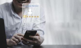 Businessman using smartphone for select smiley face icon for client evaluation and customer satisfaction after use product and service concept. photo