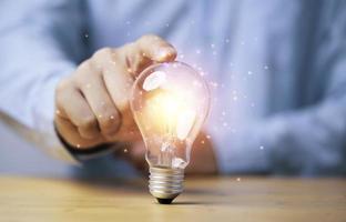 tocar a mano una lámpara brillante o una bombilla para una idea de pensamiento creativo y una solución de problemas o un concepto de solución.