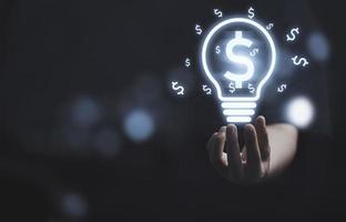 el hombre de negocios que sostiene una bombilla virtual o una lámpara con un signo de dólar para una idea creativa puede generar más concepto de dinero. foto