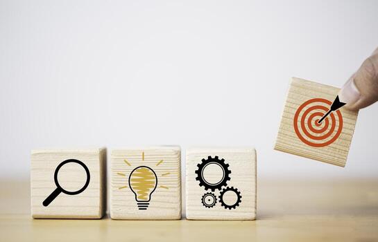 Hand putting target board which printing on wooden cube block on mechanical gear and lightbulb icon  for creative and set up business objective target  goal concept. photo