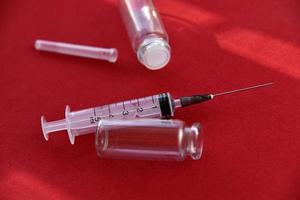 Medical syringe tablets and glass bubbles on a red background photo