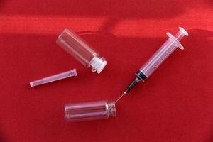 Medical syringe tablets and glass bubbles on a red background photo