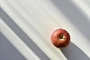 A red and yellow apple in the shadows on the windowsill photo