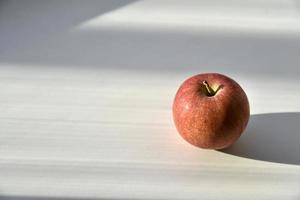 A red and yellow apple in the shadows on the windowsill photo