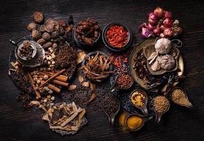 Thai native food, spices herbs, and various ingredients taken from top view angle.  Group of hot and spicy dry vegetables, nuts, and grains for making Asian food on wooden background. Dark tone photo