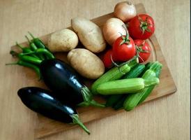 un conjunto de verduras que consta de berenjenas, calabacines, pimientos verdes, tomates rojos frescos y cebollas doradas foto