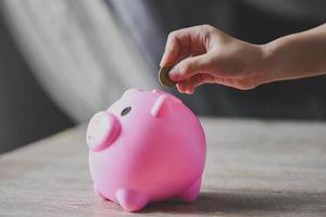 Save money concept, child hand putting money coin into piggy bank for saving money for education study photo