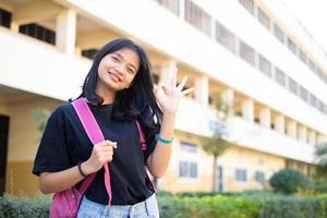 estudiante joven sostiene un libro rosa y una mochila en la escuela, de regreso a la escuela. foto