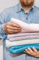 Man holds a stack of fresh terry towels. photo