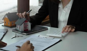 concepto de bienes raíces, el agente tiene una calculadora para el precio actual de los documentos gráficos de la tabla de inversión del préstamo y calcula el pago de la tabla al cliente foto