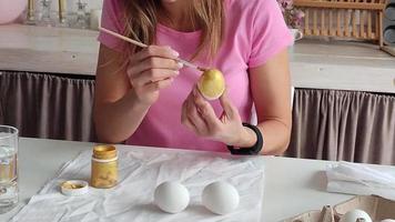 donna che colora le uova seduta in cucina video