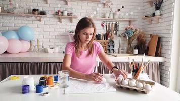 Woman coloring eggs sitting at the kitchen video