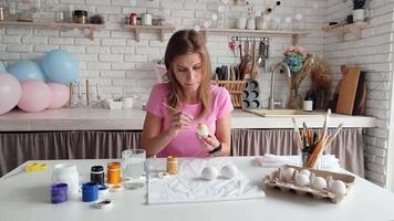 Woman coloring eggs sitting at the kitchen video