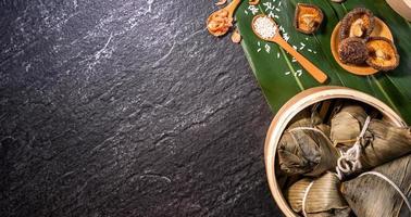 Close up, copy space, top view, flat lay. Famous asian chinese tasty handmade food in duan wu event, steamed rice dumplings shaped like pyramidal ingredient on black slate photo