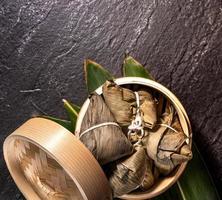 Close up, copy space, top view, flat lay. Famous asian chinese tasty handmade food in duan wu event, steamed rice dumplings shaped like pyramidal ingredient on black slate photo