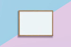 marco de madera vacío horizontal sobre fondo rosa y azul pastel, marco en blanco simulado con espacio de copia, foto