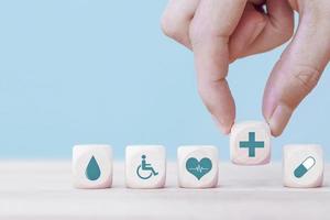 la mano elige un icono de emoticono símbolo médico de atención médica en un bloque de madera, concepto de seguro médico y de atención médica foto