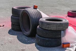 Neumáticos de coche viejos y desgastados plegados por seguridad en caso de accidentes en la pista de carreras y cubiertos con polietileno foto