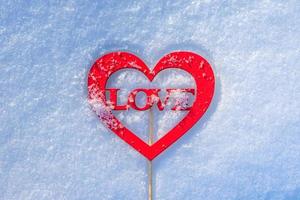 A figure in the shape of a heart with the word love lies on the snow. Love message in romantic form photo