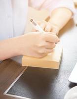 Business concept. Woman takes note for project with laptop and report in office desk. Backlighting, sun glare effect, close up, side view, copy space photo