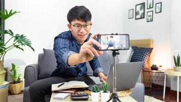 Social media influencer or blogger present and review recording or streaming vlog about product using smartphone on tripod for social media channel making live stream concept.