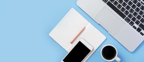 Girl write on open white book or accounting on a minimal clean light blue desk with laptop and accessories, copy space, flat lay, top view, mock up photo