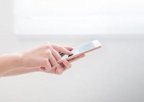 Side view of asia young business woman in blue shirt dress standing beside window and using smart phone in bright office room, copy space, close up photo