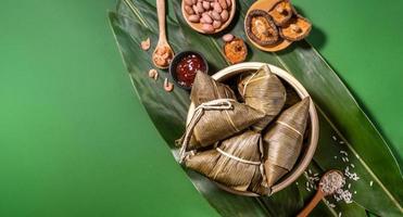 zongzi, albóndigas de arroz al vapor sobre fondo de mesa verde, comida en el concepto de duanwu del festival del bote del dragón, primer plano, espacio de copia, vista superior, capa plana foto