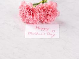 Copy space, close up, mock up, clipping path. Mothers day wording concept design. Beautiful fresh blooming baby pink color carnations isolated on bright marble background. photo