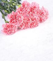 Design concept - Beautiful bunch of carnations on marble white background, top view, copy space, close up, mock up. Mothers day gift idea inspiration. photo