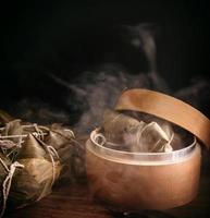 Zongzi, steamed rice dumplings in steamer on wooden table, famous tasty food in dragon boat festival duanwu design concept, close up, copy space. photo