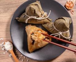 Zongzi, woman eating steamed rice dumplings on wooden table, food in dragon boat festival duanwu concept, close up, copy space, top view, flat lay photo