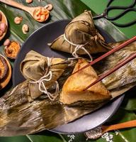Zongzi, woman eating steamed rice dumplings on green table background, food in dragon boat festival duanwu concept, close up, copy space, top view, flat lay photo