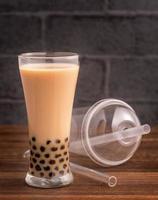 Delicious bubble milk tea with straw in drinking glass on wooden table background, concept of reduce plastic to go in Taiwan, close up, copy space photo