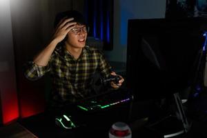 el jugador asiático con auriculares estresado con la mano se siente deprimido o enojado cuando pierde el videojuego en la computadora miedo y malestar por error, tecnología de videojuegos y concepto de deporte electrónico