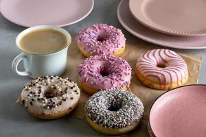 Several donuts lie on craft parchment paper on gray surface photo